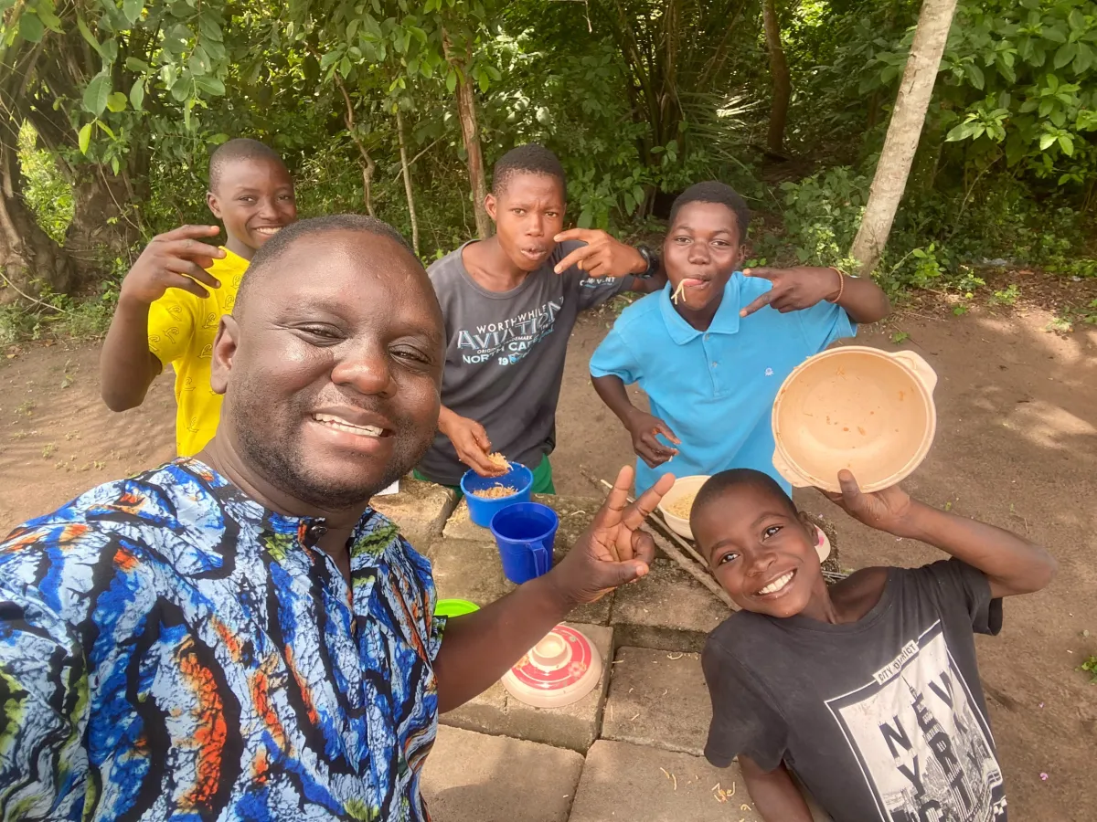 A Happy Kids team member and children smiling together at the camp in Togo